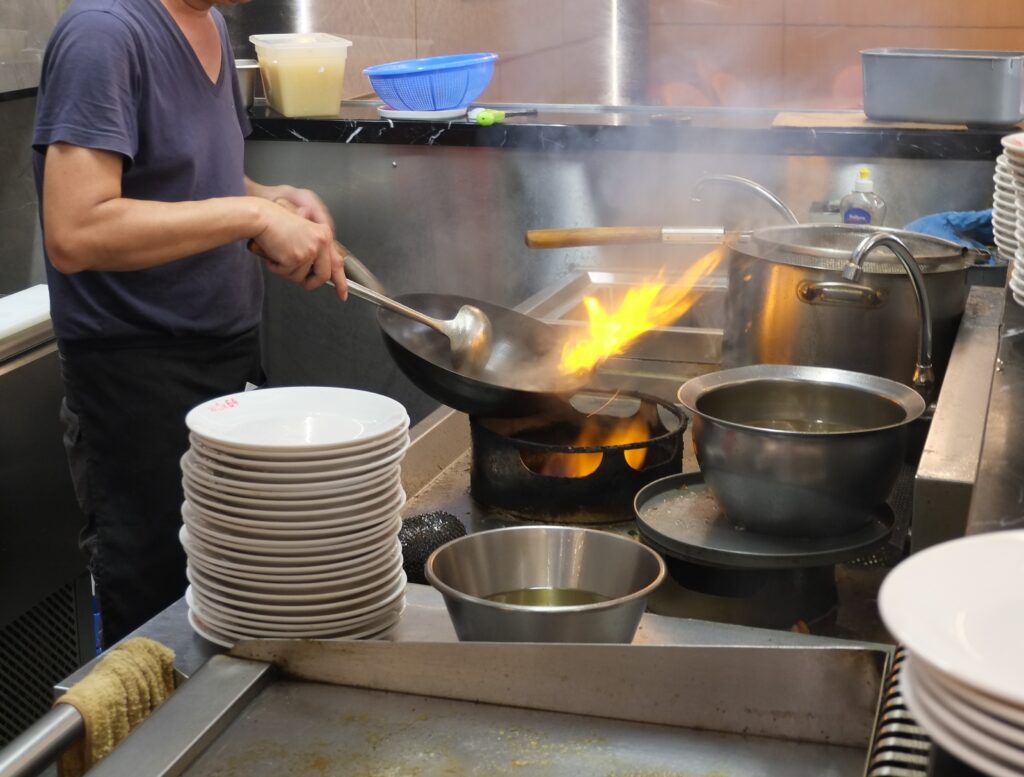Le cuisinier saisit une assiette au wok